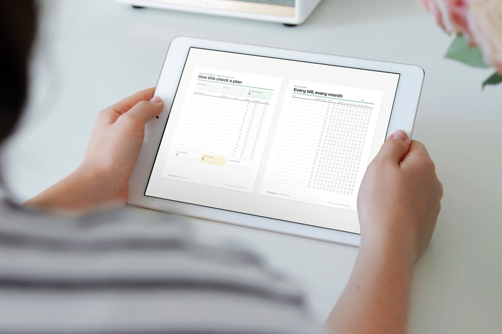 Hands holding an iPad with the printable budget planner open in a notebook app