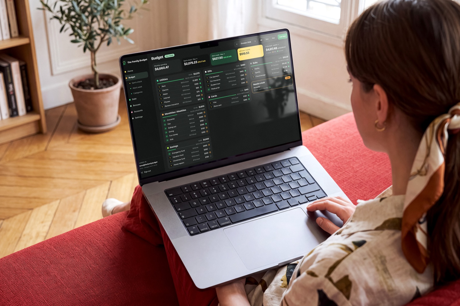 A woman on a couch using The Family Budget on her laptop
