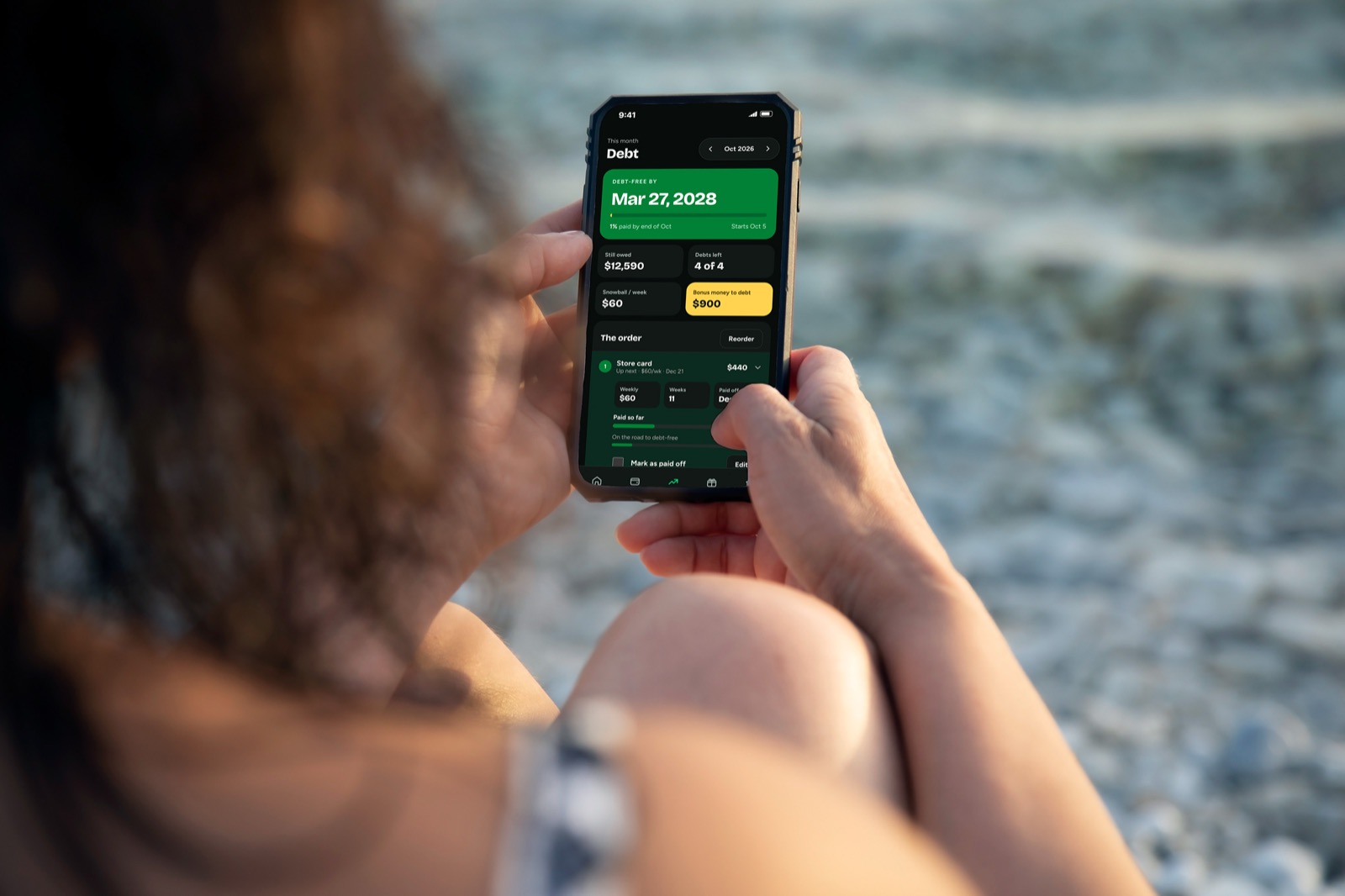 Someone holding a phone showing a debt-free date of March 27, 2028