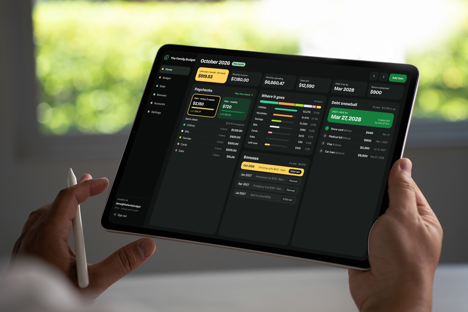 Hands holding a tablet with The Family Budget home screen